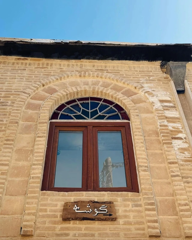 نمای آجری و قدیمی اقامتگاه سنتی گوشه شیراز با یک پنجره چوبی
