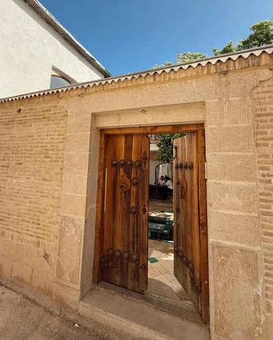 ورودی اقامتگاه سنتی گوشه شیراز با یک درب چوبی بزرگ