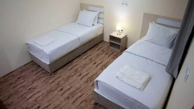 اتاق دو تخته با روتختی های سفید در هتل آپارتمان پدر من بوشهر