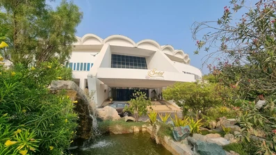 نمای ساختمان سفید هتل صدف کیش از میان فضای سبز