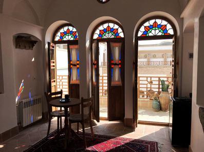 سه پنجره سنتی با معماری ایرانی و شیشه هیا رنگی که رو به حیاط عمارت سنگ پلوی کاشان باز می شود