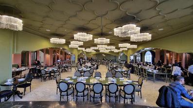 صندلی های کلاسیک با پارچه ابی آسمانی و لوسترهای طلایی در رستوران هتل سیب و نار یزد