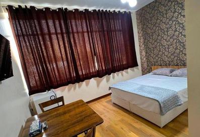 تخت دو نفره سفید رنگ در اتاق تویین هتل ترن. پرده زرشکی رنگ در تصویر دیده می شود.