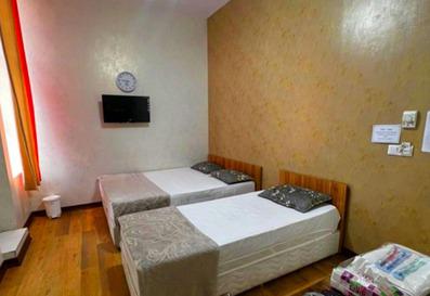 دو تخت یک نفره با ملافه سفید رنگ در کنار هم در اتاق دوبل هتل ترن تهران