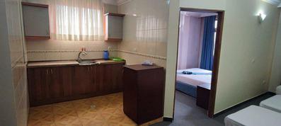 سینک ظرفشویی در سوییت 5 تخته هتل زاگرس که با کابینت و یخچال قهوه ای رنگ تجهیز شده است. قسمتی از تخت دو نفره در اتاق کنار سوییت قابل مشاهده است.