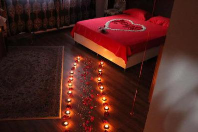 اتاق ماه عس هتل احمد با فضایی قرمز رنگ، شمع های روشن در فضای تاریک اتاق در کیف چیده شده اند.